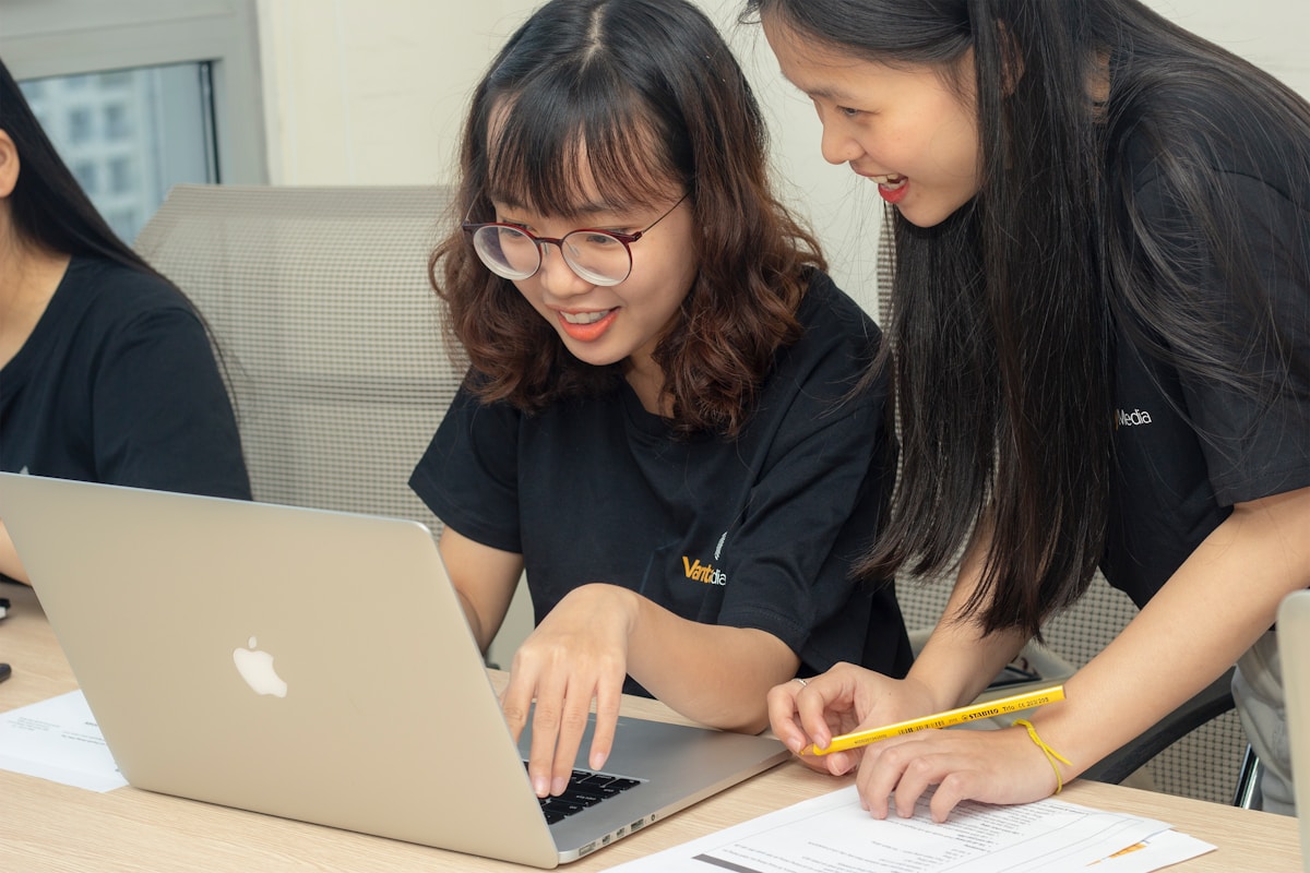 Students working together on a laptop while reviewing study material