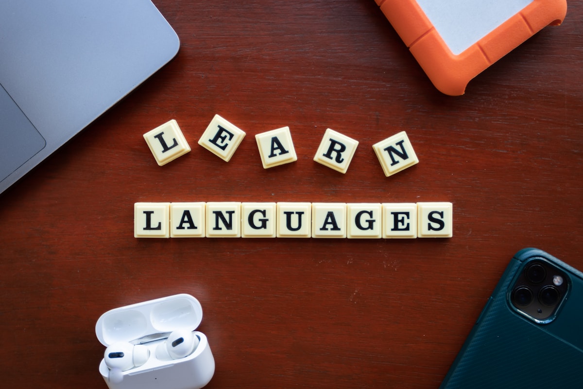 Letter tiles spelling learn languages on a desk with a laptop and earphones