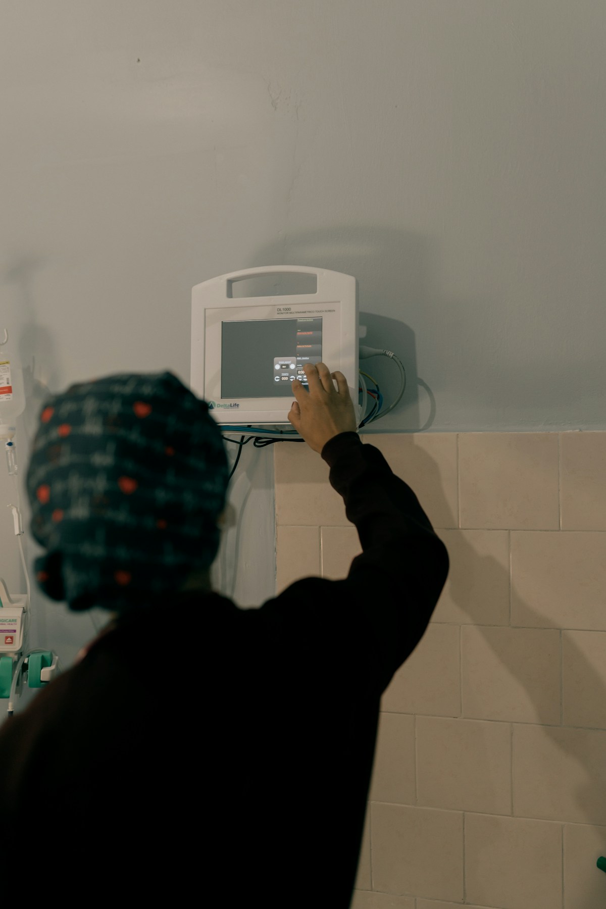 Hand adjusting a patient monitor screen in a hospital room