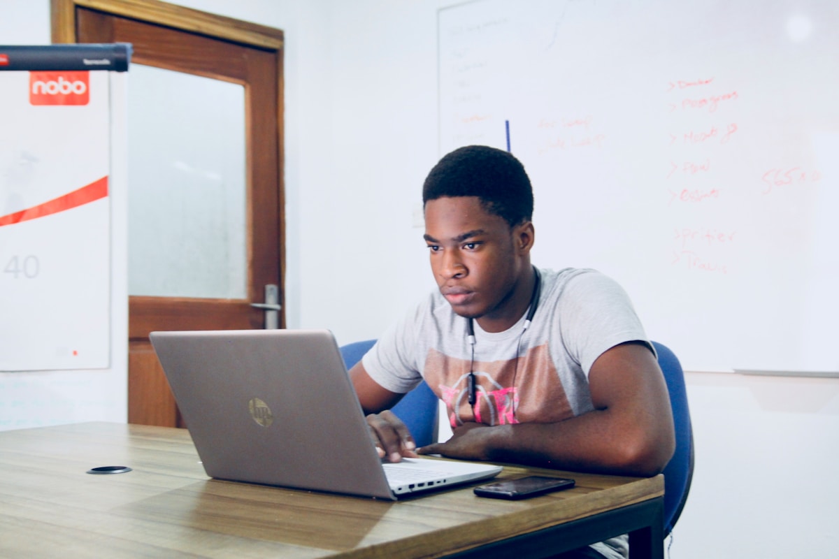 Student studying with a laptop and notebook at a desk without expensive materials