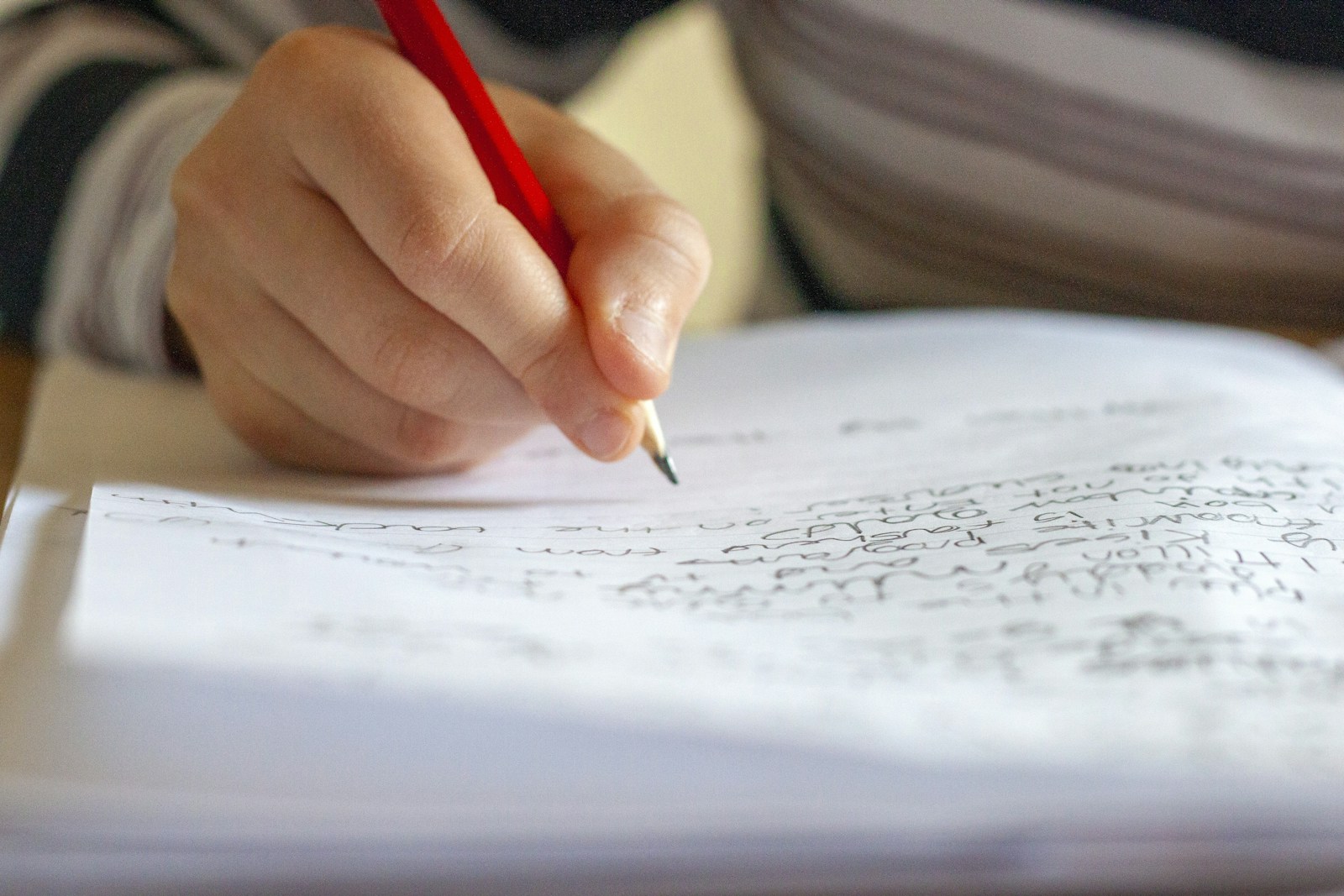 Person writing on paper at a desk, focused on academic work