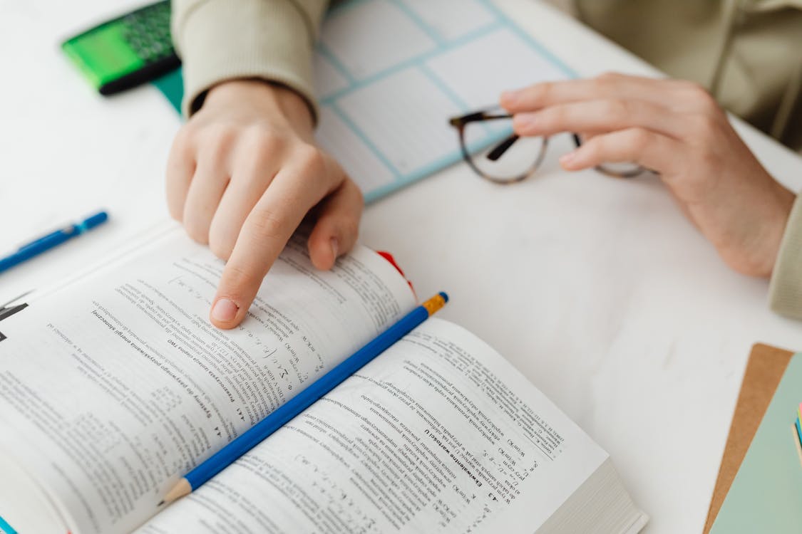 Student reading a large book intensely at a study desk
