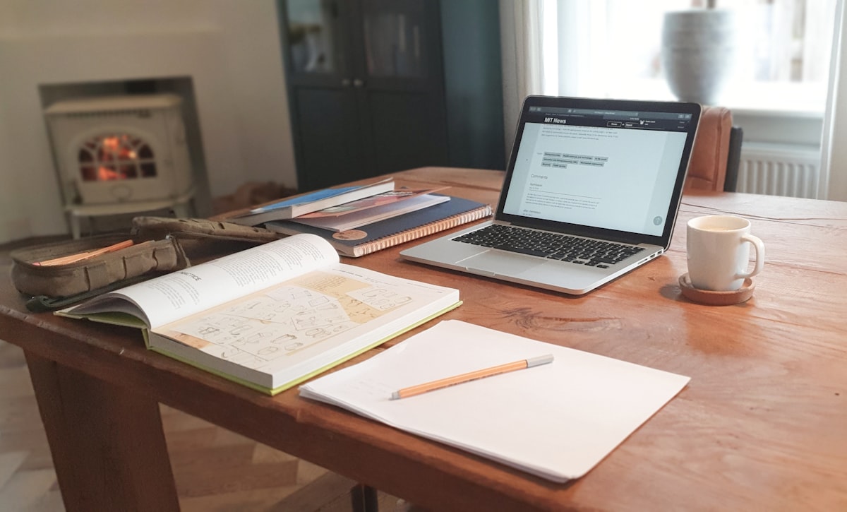 Student studying at a desk with multiple books and notebooks