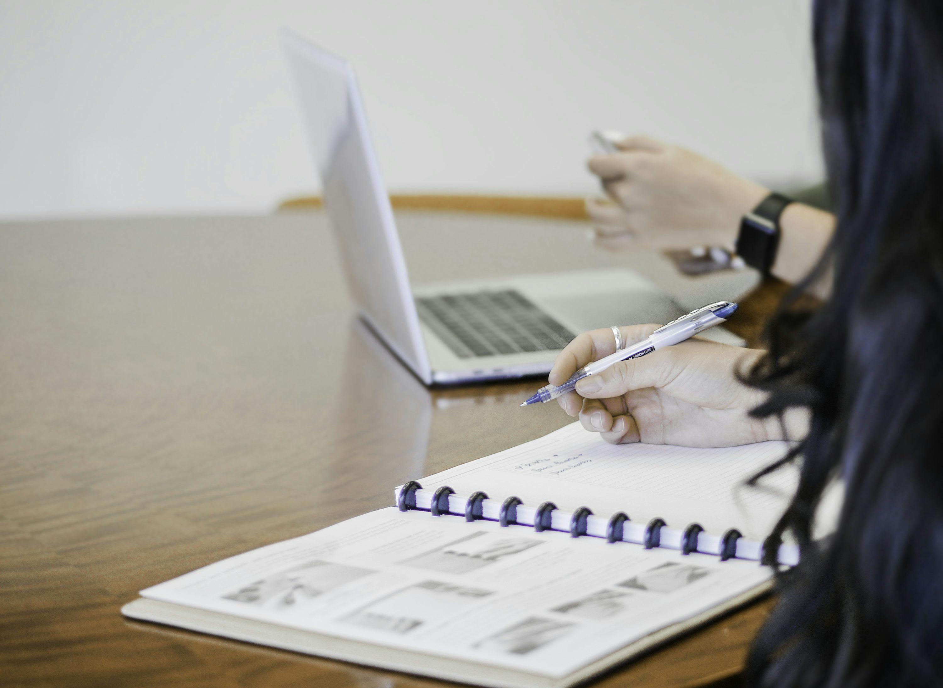 Person writing accounting notes on paper with a pen