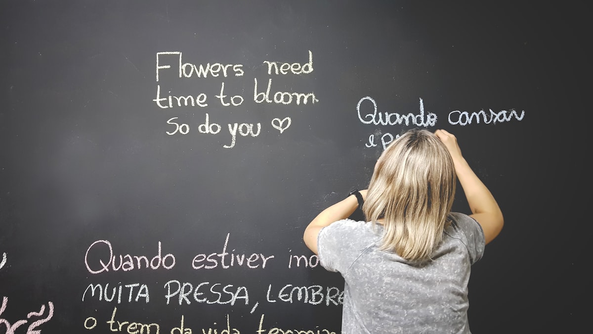 Person writing on a chalkboard, practicing language learning