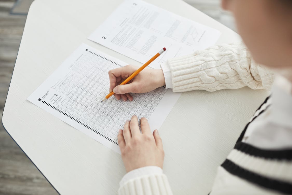 Person taking a written exam with a pen on an answer sheet
