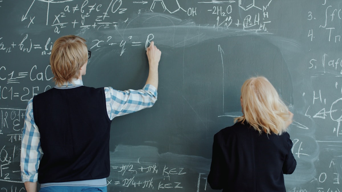 Teacher writing on a chalkboard preparing for exam