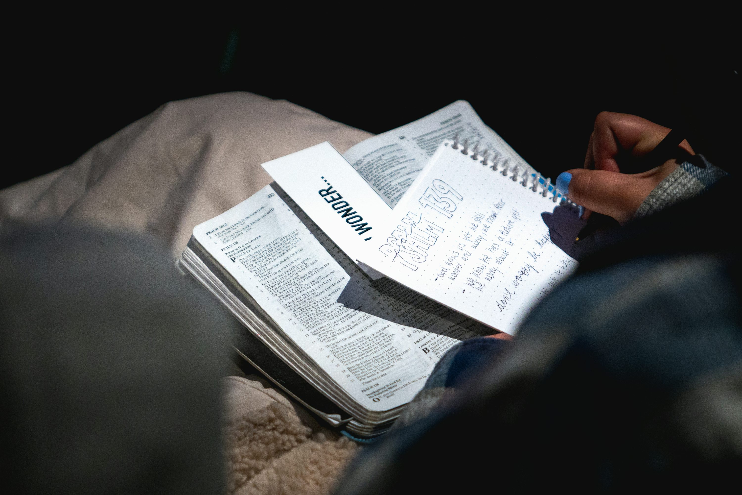 Person writing notes and reviewing highlights in a notebook