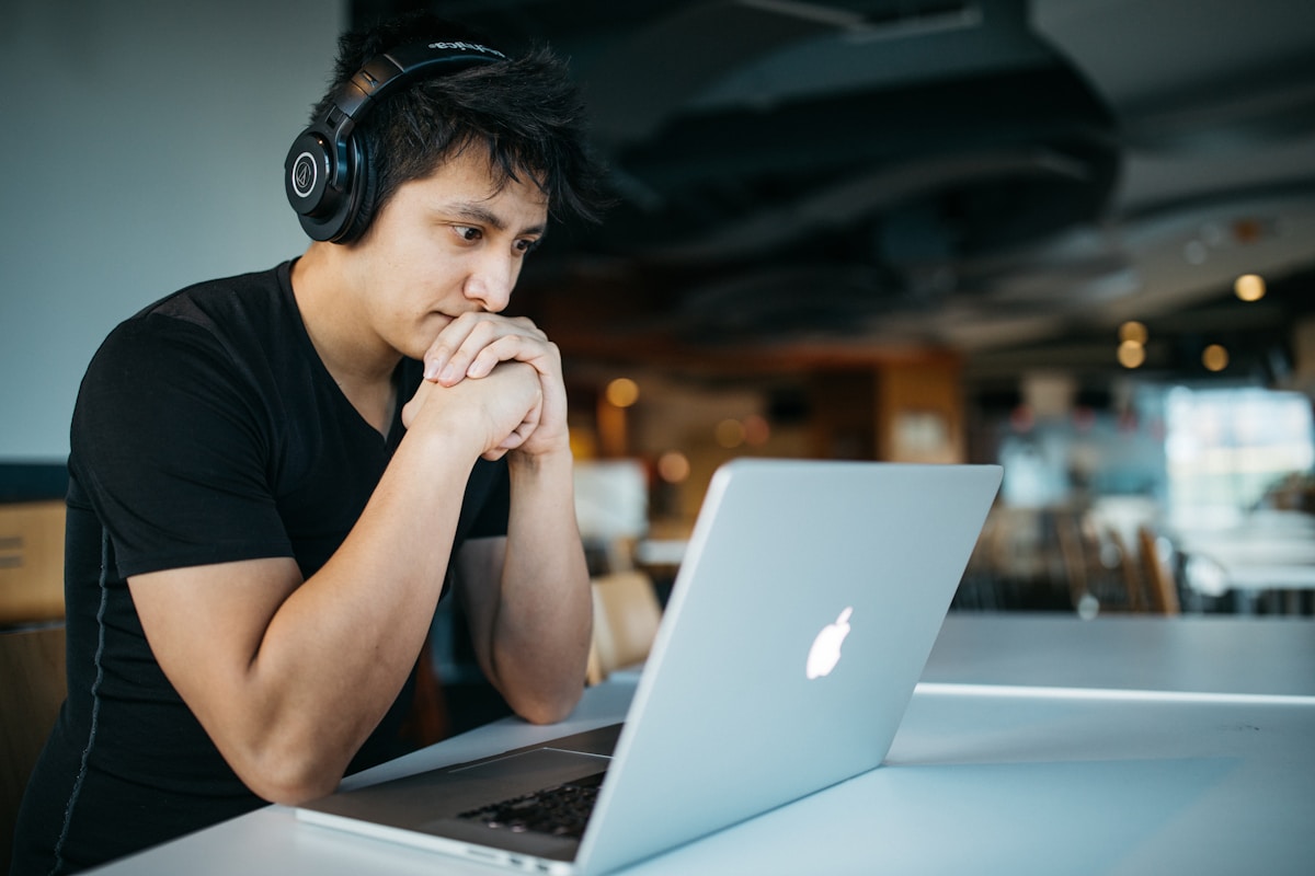 Language learner wearing headphones concentrating on a listening exercise at a laptop