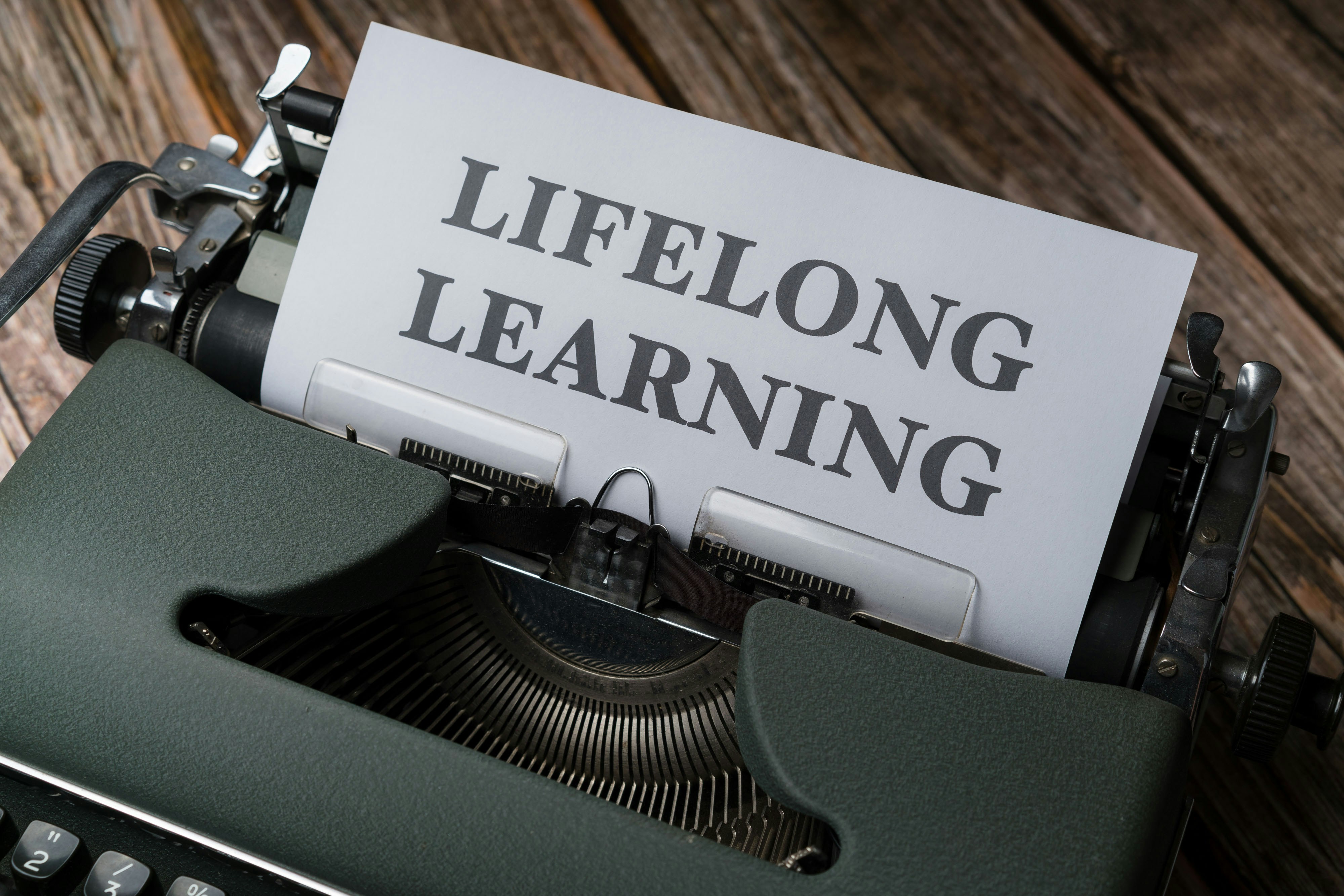 Typewriter with paper reading 'lifelong learning' representing continuous professional development