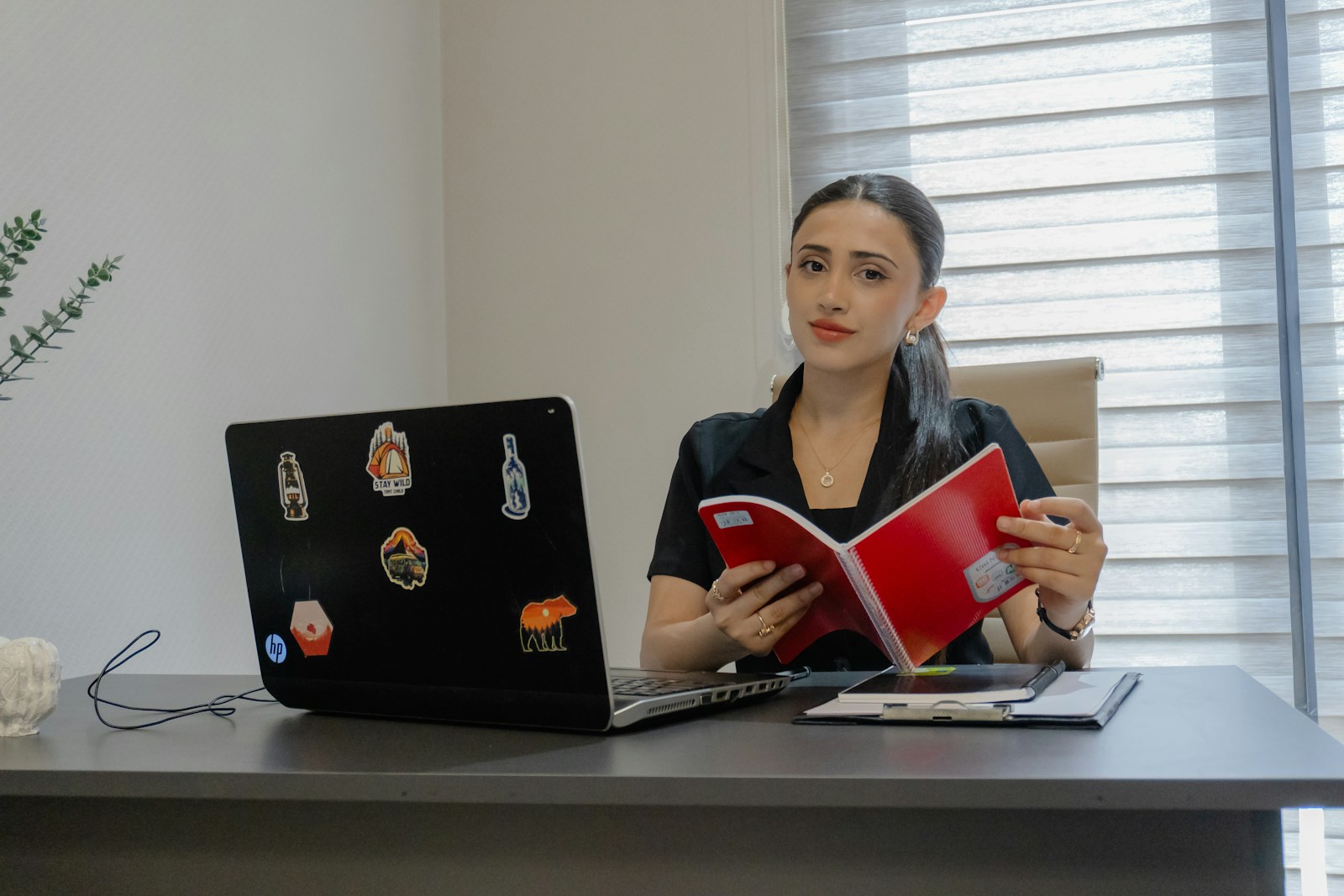 Professional woman reading a book at her office desk, representing continuous workplace learning