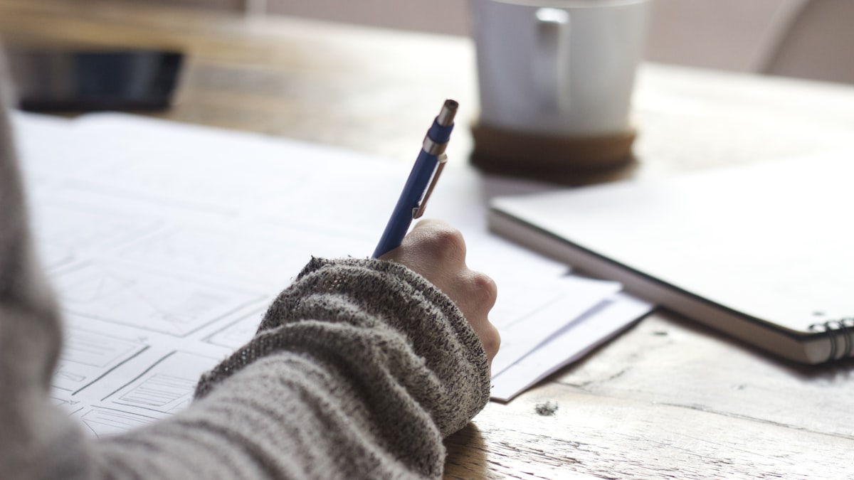 Person writing at a desk practicing repeated review of study material