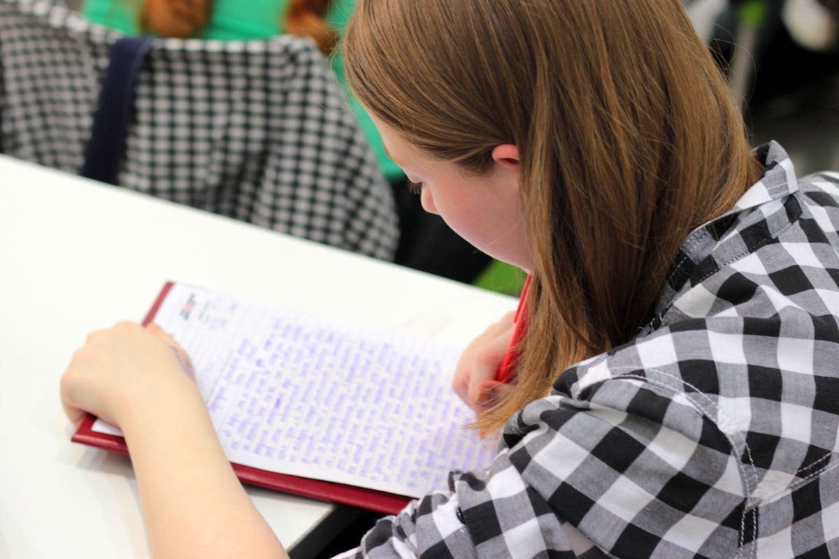 Woman writing on paper with a pen at a desk