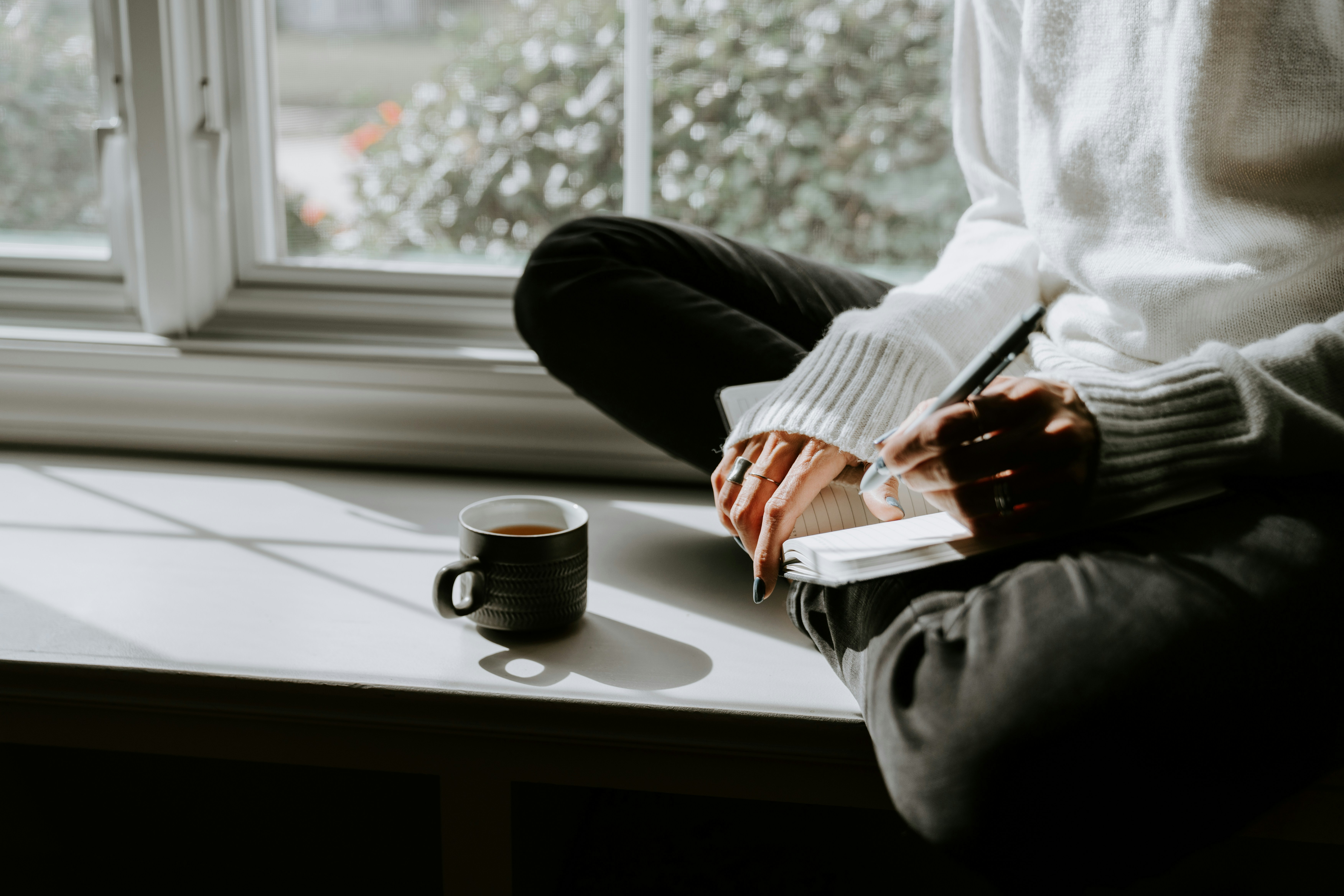 Person studying by a window in natural morning light with a cup of coffee