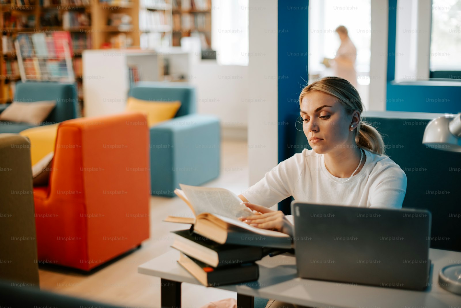 A woman sitting at a table reading and studying a book