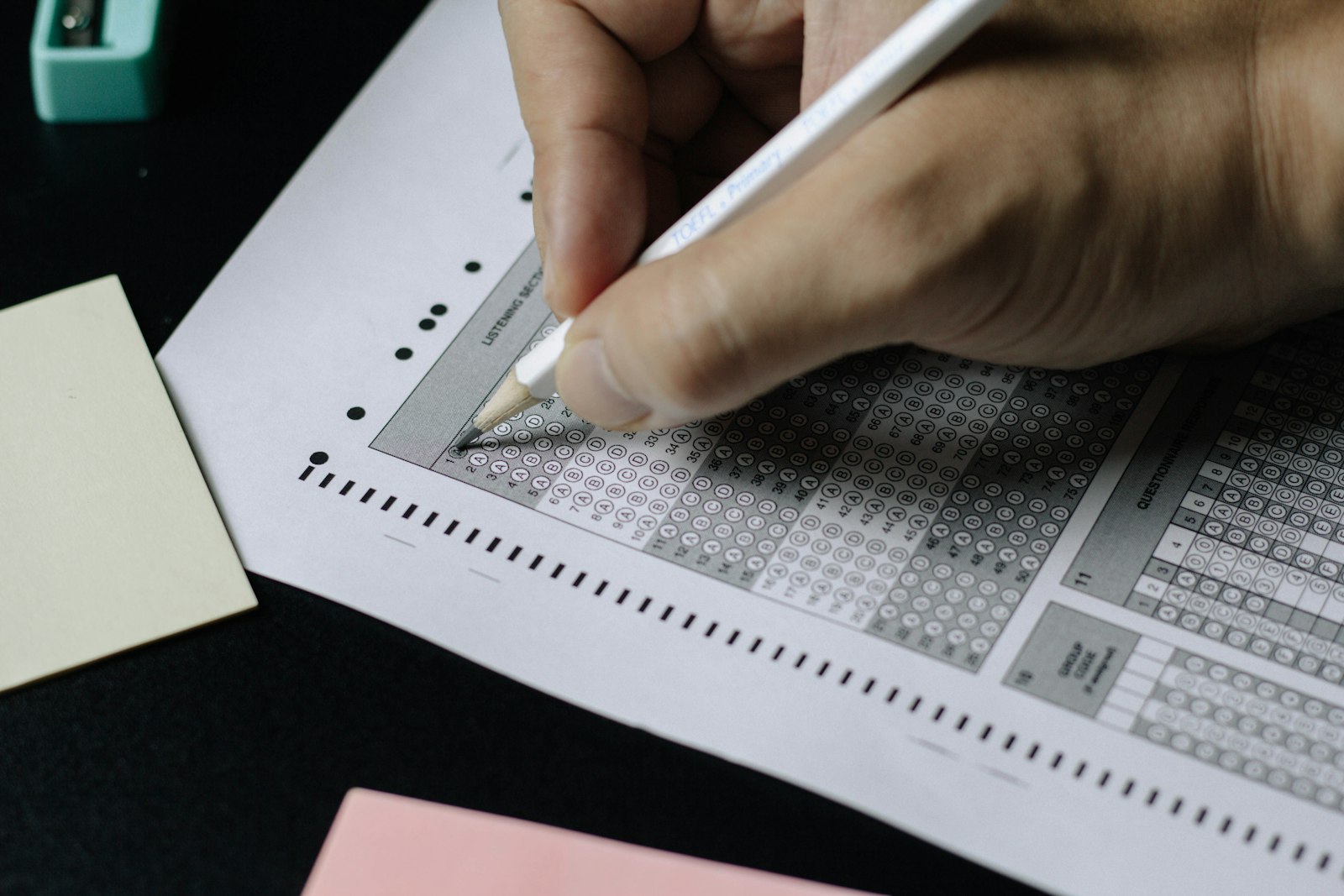 Person writing carefully on exam paper with a pen