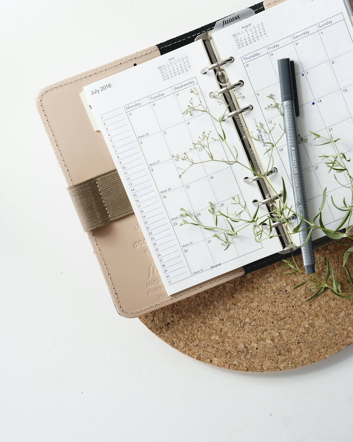 Weekly planner open on a desk with a pen and calendar for scheduling study time